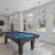 a room with a pool table and chairs